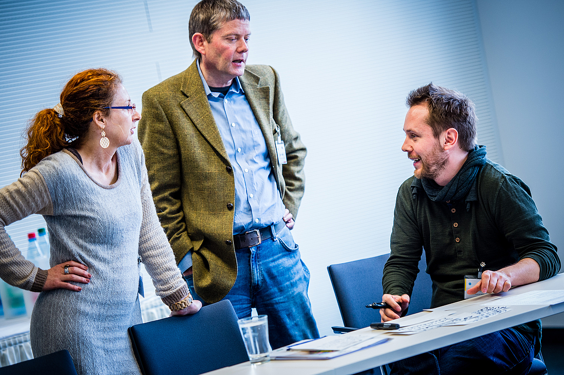 Eine Frau und zwei Männer besprechen eine Aufgabe im Workshop.
