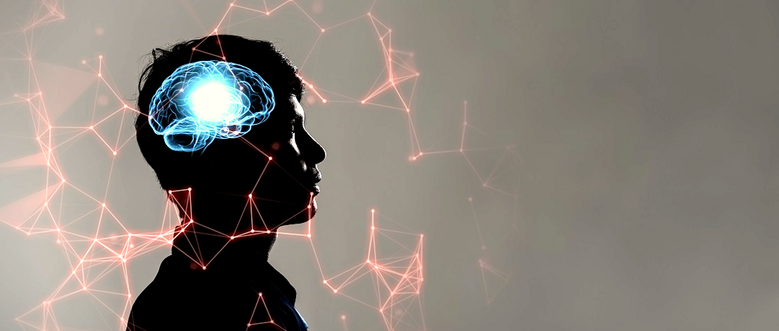 Viele rote miteinander verbundene Punkte bilden ein Netzwerk. Sie umschwirren die Silhouette eines Kopfes. Im Kopf leuchten die Synapsen blau auf.