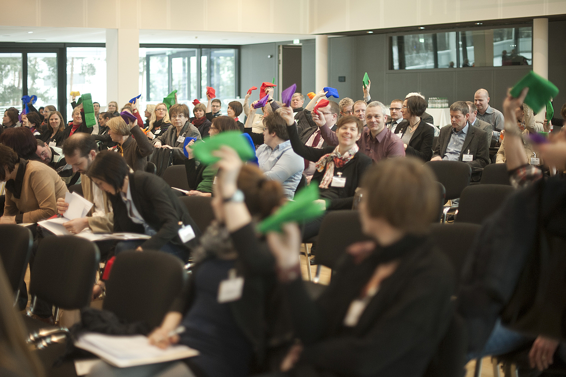 iga.Kolloquium 2013: Das Publikum im Veranstaltungssaal erhält Tücher in verschiedenen Farben.