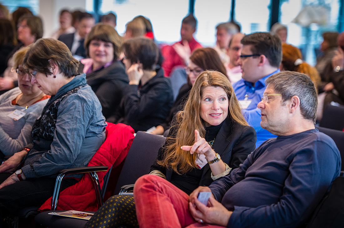 Eine Teilnehmerin unterhält ich angeregt mit ihrem Sitznachbarn.