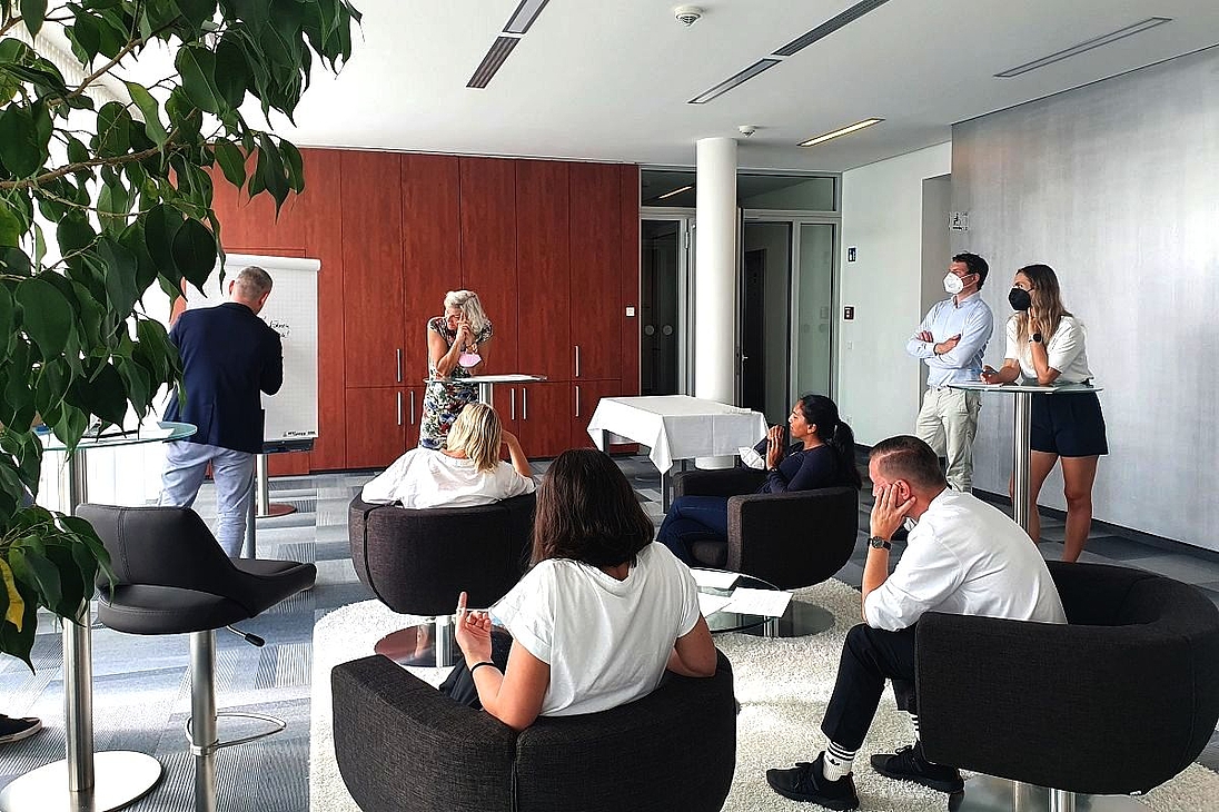 iga.Expertendialog 2022: Eine Gruppe aus acht Personen arbeitet konzentriert an einer Fragestellung. Ein Teilnehmender notiert Gedanken am Flipchart.