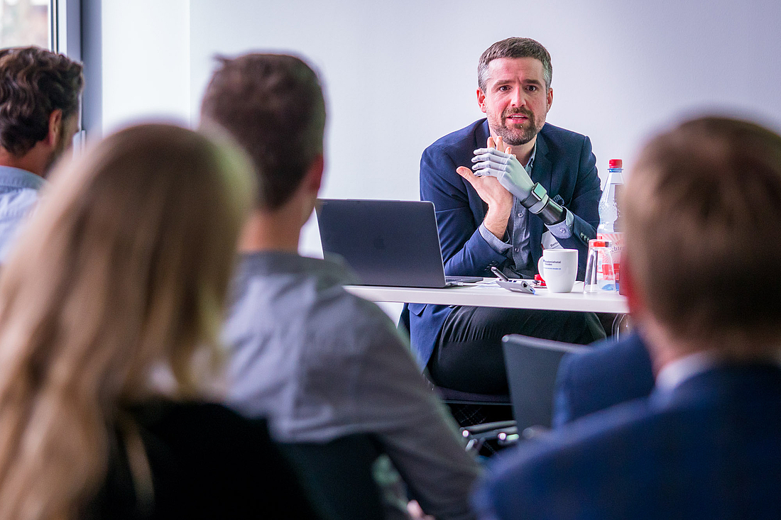 iga.Kolloquium 2017: Der Referent spricht vor den Teilnehmenden am Workshop. Anstelle seiner linken Hand trägt er eine Handprothese.
