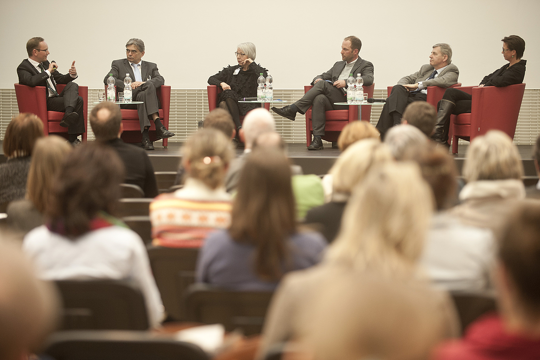 Blick über das Publikum auf die Diskussionsrunde auf der Bühne.