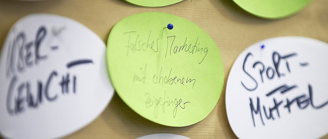 Kärtchen mit der Aufschrift: Übergewicht, Sportmuffel, falsches Marketing mit erhobenem Zeigefinger.