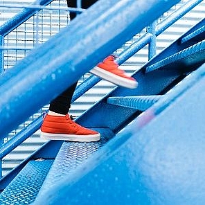 Ein Mensch mit roten Turnschuhen läuft eine Außentreppe hinauf.