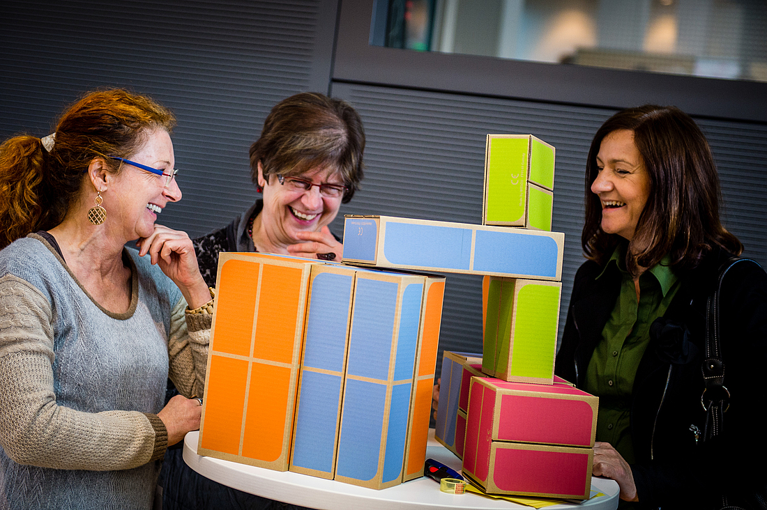 Teilnehmerinnen stapeln farbige Bauklotze übereinander.