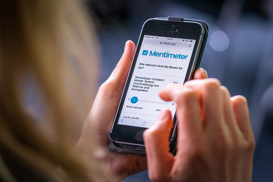 iga.Kolloquium 2017: Eine Teilnehmerin nimmt an einer Abstimmung über eine Eingabe in ihr Smartphone teil.