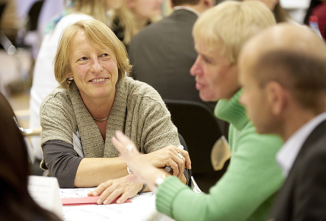 Teilnehmende diskutieren an den Workshop-Tischen.