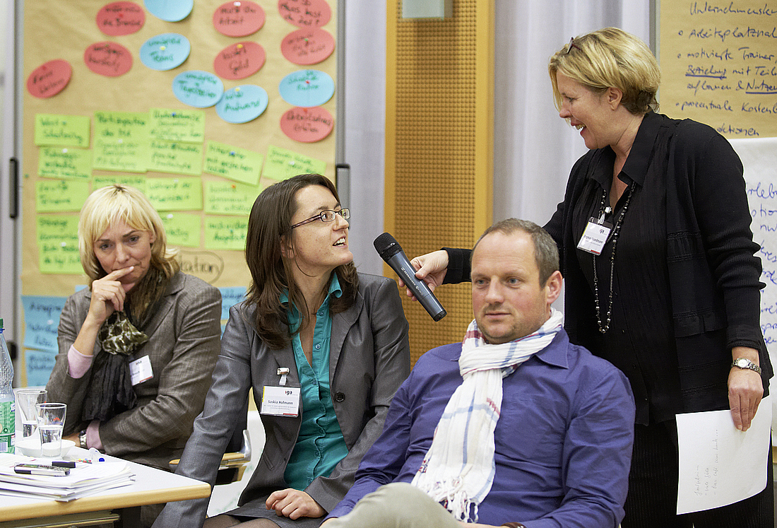 Die Moderatorin befragt eine Workshop-Teilnehmerin zu den Diskussionsergebnissen.