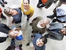 Eine Gruppe von Frauen und Männern steht in einem Kreis. Alle blicken nach oben.
