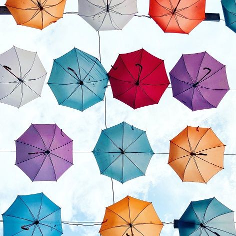 Viele bunte Regenschirme überspannen eine Straße.