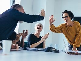 Ein Team in einem Besprechungsraum applaudiert.